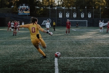 Female soccer goalie kicking the ball from the corner of the box to teammates on the field