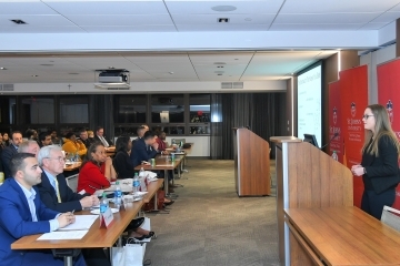 Female student standing infront of room or students and faculty making a presentation.