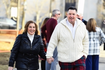 Alumni couple holding hands on campus