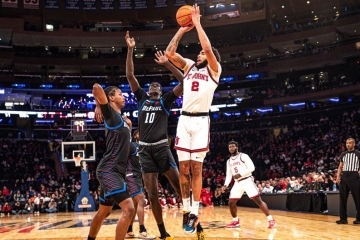 St. John's Basketball player #2 taking a shot on the court as two DePaul defensemen try to block it.