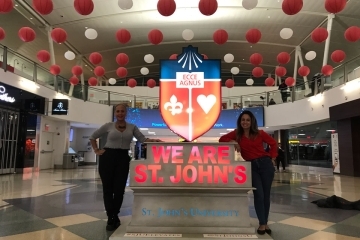 Odaris Ithier-Olle and Elena Damiani next to St. John's crest statue in JFK Airport