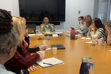 Dr. Stephanie Dunson sitting at the head of the table speaking to other faculty members sitting