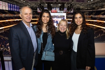Three females and a male posing for a photo on the overlook deck at UBS arena