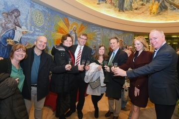 Four couples toasting together in lobby of St. Thomas More Church
