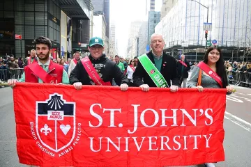 4 St. John's Community members holding St. John's University banner in St. Patrick's Day Parade