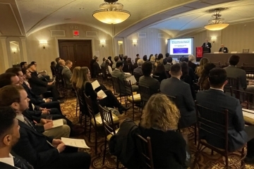 Seated audience members and speakers at a St. John's Law symposium.