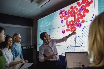 Male faculty member pointing at screen while students look on