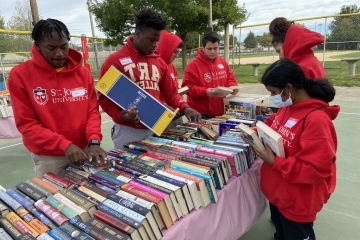 University Service Day volunteers at a table full of books