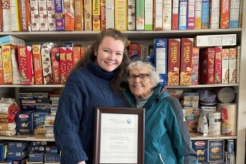 St. John's University Grace Pigott ’19C, ’23GEd holding plaque with another woman standing in food pantry