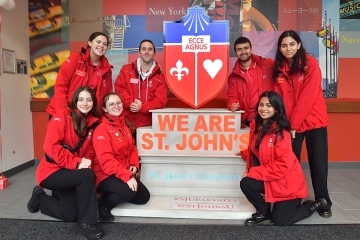 Admissions Ambassadors in Red Jackets posing with "We Are St. John's" statue