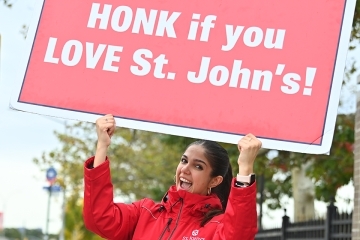 Admissions ambassador holding up "honk if you love St. John's" sign
