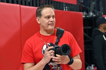Wendell Cruz, Esq. ’91SVC, holding a camera on the sidelines of Carnesecca Arena