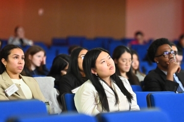 Students looking up at a screen, in blue seats