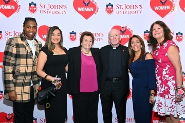 Female honorees from the St. John's Women's Lunch infront of step and repeat with Fr. Shanley