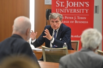  Leszek Balcerowicz, Ph.D. ’74CBA speaking at table to St. John's students and staff