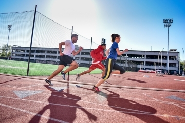 Three students running on the track of DaSilva Field