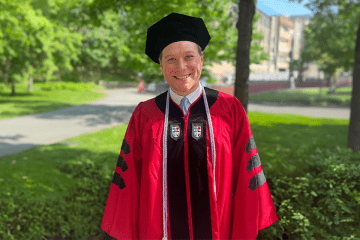 St. John's Law alumnus Seth Goldstein wearing a red graduation gown with black detailing and a black tam.