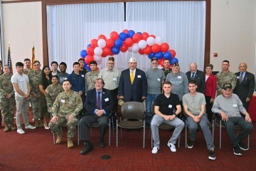 St. John's ROTC and community members pose with veterans for a photo in front of a balloon arch