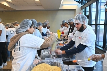 Students helping pack meals at the Protiviti food packing event