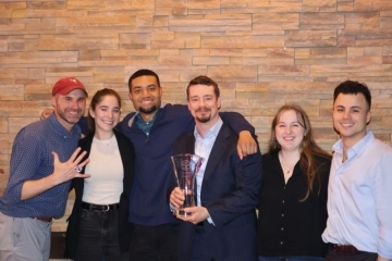 Justin Fuller, holding an award, stands with fellow student advocates and coaches at a mock trial competition.
