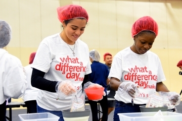 Two women helping package food in assembly line