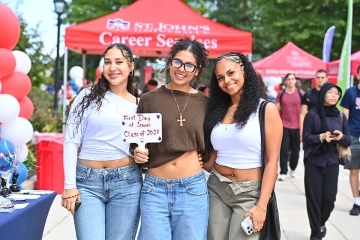 Three St. John's students holding a First Day of School sign
