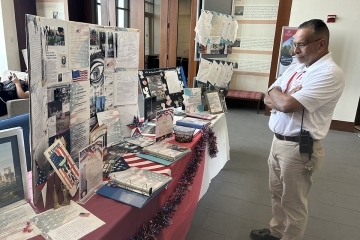 Man in white polo looking at table of 9/11 Student Reflections