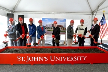 St. John's employees and Fr. Shanley wearing construction hats and using shovels