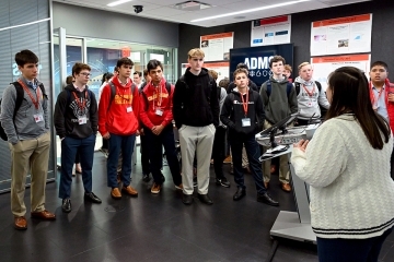 Group of young boys listening to a female faculty member
