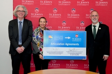 2 men and 1 woman standing next to a board 
