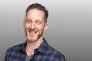Headshot of a man behind a grey background