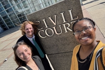 Three St. John’s Law CLARO volunteers outside the Queens Civil Courthouse.