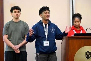 Three St. John's students present at a podium