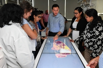 College faculty and instructors receive training from an Anatomage expert on the Anatomage table