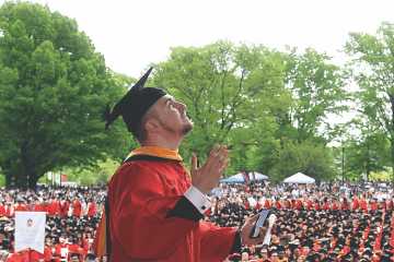 Male student walking across stage while looking up