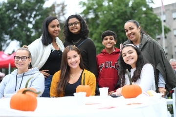 Group shot of 7 student and family members painting pumpkins