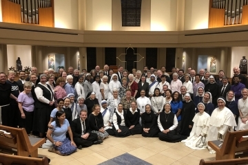 Students sitting on the church floor with the Sisters and Brothers serving the local Church