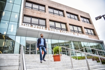 student_walking_down_stairs_infront_of_the_peter_j_tobin_college_of_business