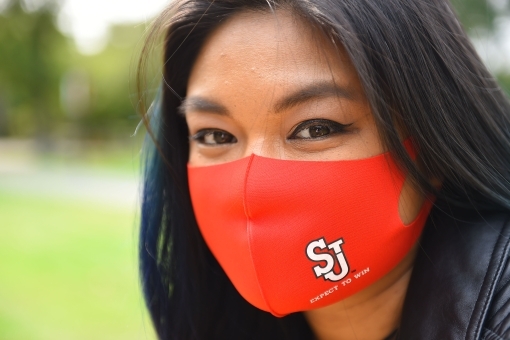 Female student wearing red face mask with the St. John's Athletics logo