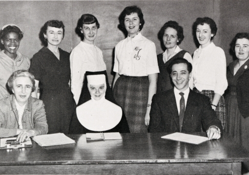 College of nursing students standing infront of desk for photo. 
