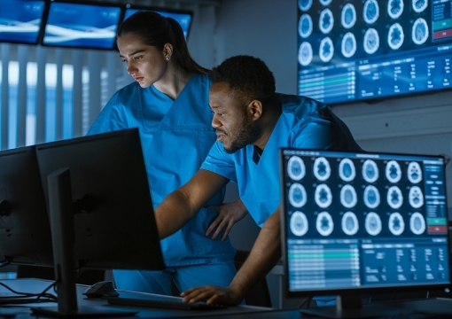 Male and Female in scrubs looking at computer monitor