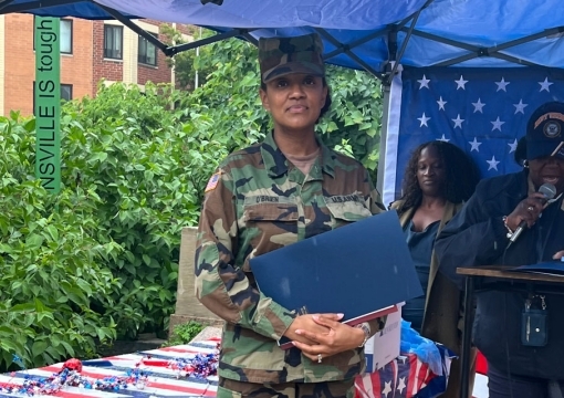 Sammantha O’Brien McCalla ’99CBA, ’01MBA, ’20Ph.D. in uniform standing under a blue tent on the St. John's campus
