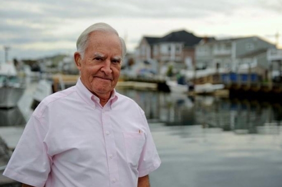 ollon dowling posing for photo by body of water with boats