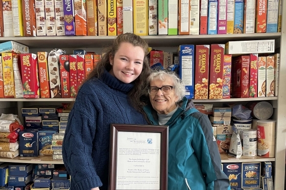 St. John's University Grace Pigott ’19C, ’23GEd holding plaque with another woman standing in food pantry