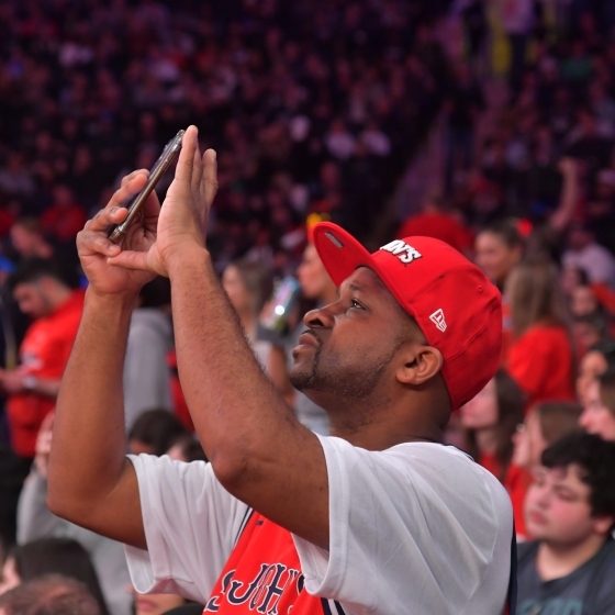 St. John's Red storm sports fans in a crowd, focusing in on a fan taking a picture