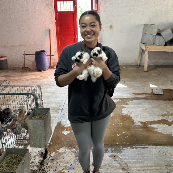 College student holding bunnies during a service trip