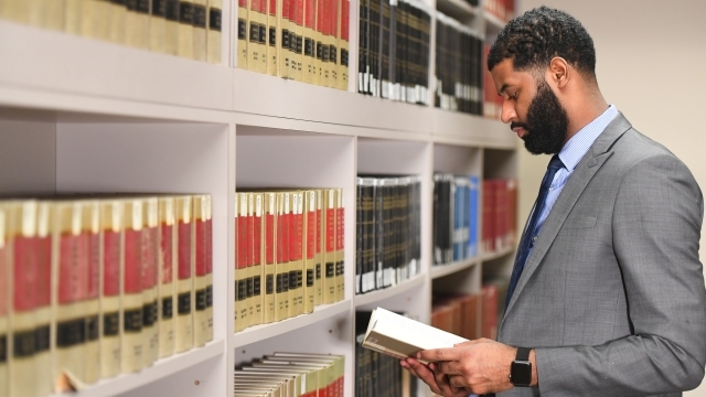 Male student in law library reading book 