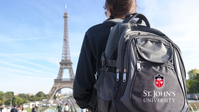 Student wearing St. John's University backpack infront of Eiffel tower