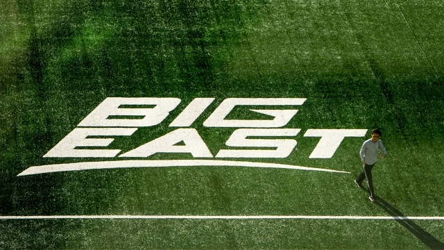 Student walking on grass with BIG EAST 