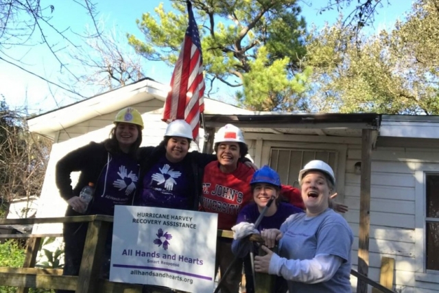 Students infront of a house with a All Hands and Hearts sign